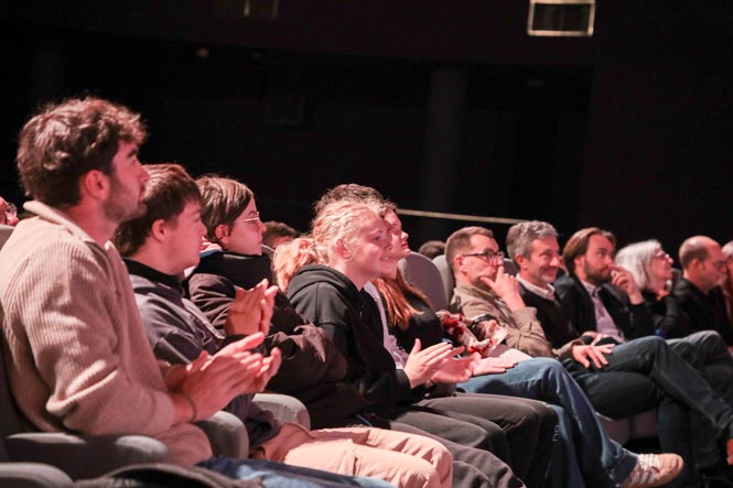 Des élèves assis dans la salle de cinéma applaudissent