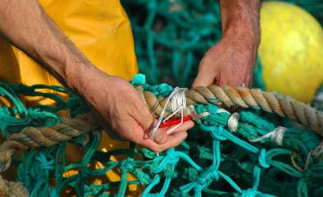 Des mains réparent un filet de pêche