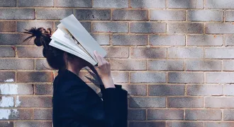 Une personne se couvre le visage avec un livre