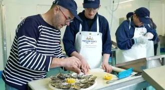 Un formateur explique la préparation d'un plateau de fruits de mer à un apprenti