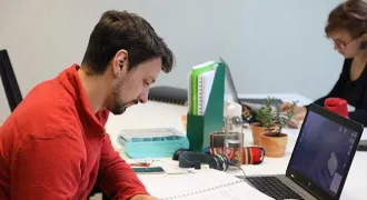 Deux étudiants travaillent face à face à une table au campus connecté