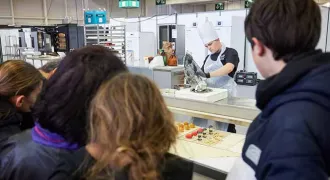 Groupe d'élèves regardant un candidat cuisinier à la Compétition des métiers