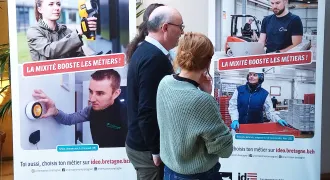 Un groupe de personnes devant la série de portraits "La mixité booste les métiers!"