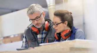 Un homme et une femme avec des casques anti-bruit regardent un document