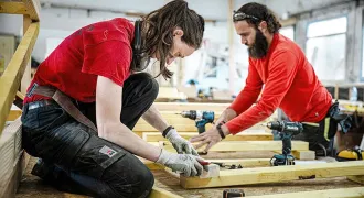 Un homme et une femme travaillent sur une structure en bois