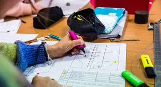 Une main d'élève annote un plan
