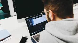 Un homme de dos regarde son ordinateur portable