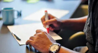 Une main écrit sur un cahier