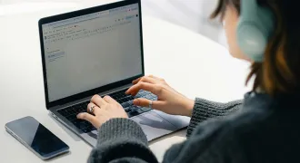 Une élève devant son ordinateur avec des écouteurs sur ses oreilles