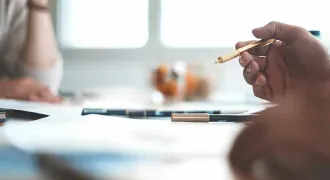 Des mains à une table note quelque chose sur un carnet