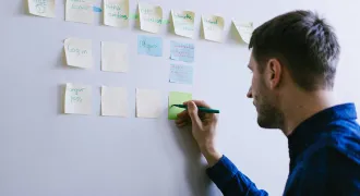 Un homme écrit sur des post-it affichés au mur