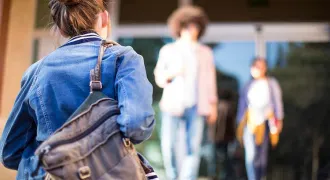 Une étudiante avec un sac à dos monte les marches d'une université