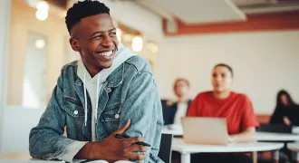Un élève au premier rang d'une classe sourit en regardant vers la droite
