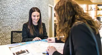 Une réceptionniste derrière son comptoir parle avec une cliente