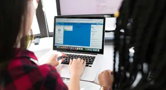 Une professionnelle travaille sur un écran avec une jeune à côté