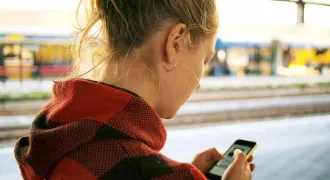 Une étudiante regarde son smartphone dans la rue