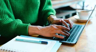 Deux mains de femme tapent sur le clavier d'un ordinateur portable