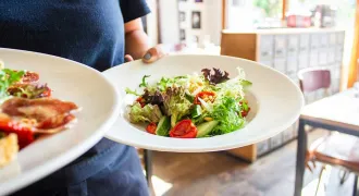 Des mains d'une serveuse apportent deux plats dans un restaurant