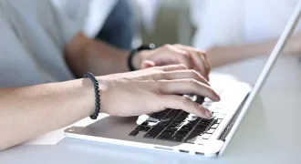 Deux mains tapent sur un ordinateur portable