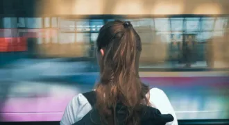 Une jeune fille avec un sac à dos devant un train