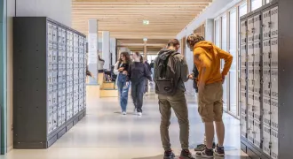 Des élèves parlent ensemble dans un couloir, devant leurs casiers