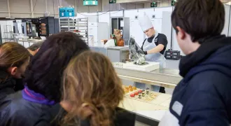 Des élèves regardent un pâtissier travailler à la Compétition des métiers