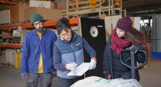 Marie note sur un cahier les références d'une fenêtre qui arrive en ressourcerie