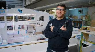 Portrait de Matias avec des outils devant un bateau de plaisance