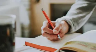 Gros plan sur une main qui prend des notes dans un cahier