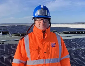 Portrait de Jean-Claude Morel devant une étendue de panneaux photovoltaïques