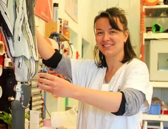 Agathe Le Gourières tient une prothèse de jambe sur l'établi de son atelier