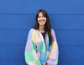 Portrait de Bertille Hinge devant un mur bleu