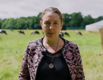 Portrait d'Aurore dans un champ avec des vaches en arrière plan