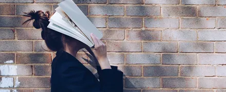 Une personne se couvre le visage avec un livre