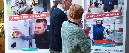 Un groupe de personnes devant la série de portraits "La mixité booste les métiers!"