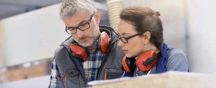 Un homme et une femme avec des casques anti-bruit regardent un document