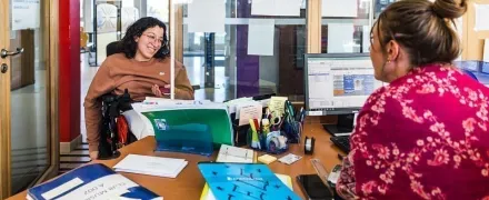 Une lycéenne en fauteuil roulant électrique lors d'un échange avec une conseillère principale d'éducation dans le bureau de la vie scolaire.