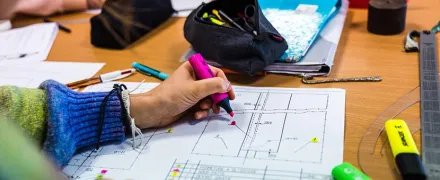 Une main d'élève annote un plan