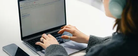 Une élève devant son ordinateur avec des écouteurs sur ses oreilles