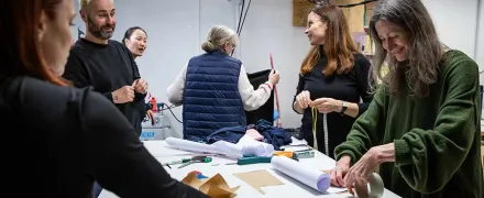 Des personnes autour d'une table avec des ciseau et un mètre mesureur