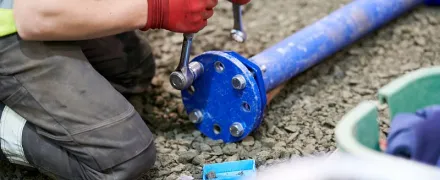 Des mains manipulant un tuyau et des outils