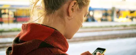 Une étudiante regarde son smartphone dans la rue