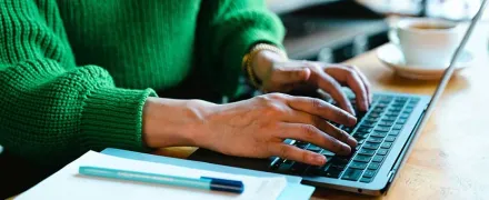 Deux mains de femme tapent sur le clavier d'un ordinateur portable