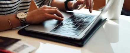 Des mains de femme tapent sur le clavier d'un PC portable