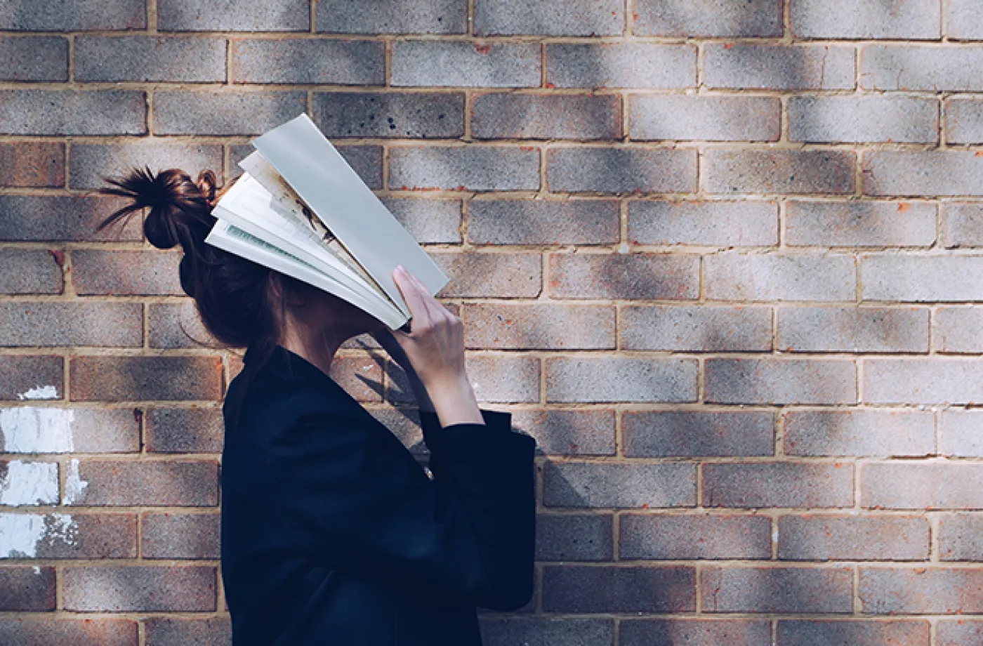 Une personne se couvre le visage avec un livre