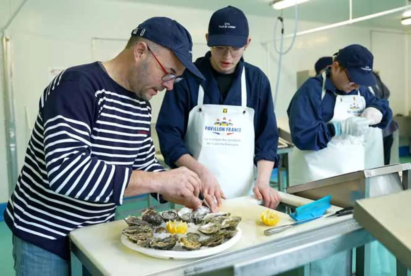 Un formateur explique la préparation d'un plateau de fruits de mer à un apprenti