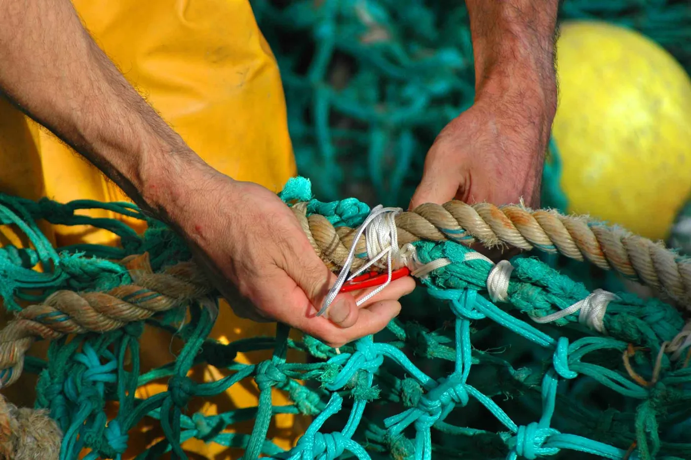 Des mains réparent un filet de pêche