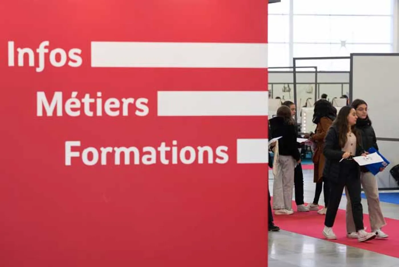 Vue d'un salon d'orientation avec un panneau indiquant "Infos métiers formations"