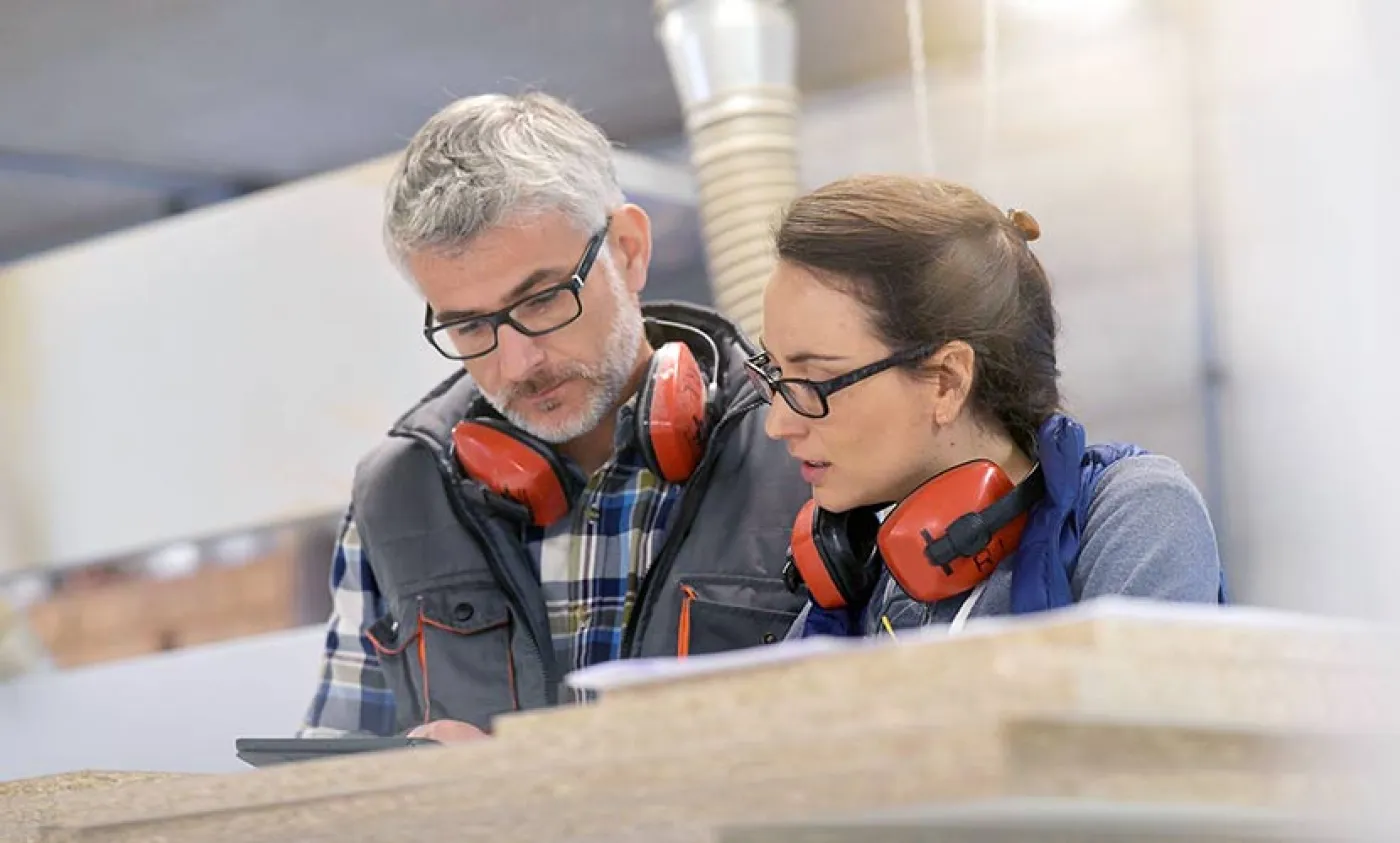 Un homme et une femme avec des casques anti-bruit regardent un document