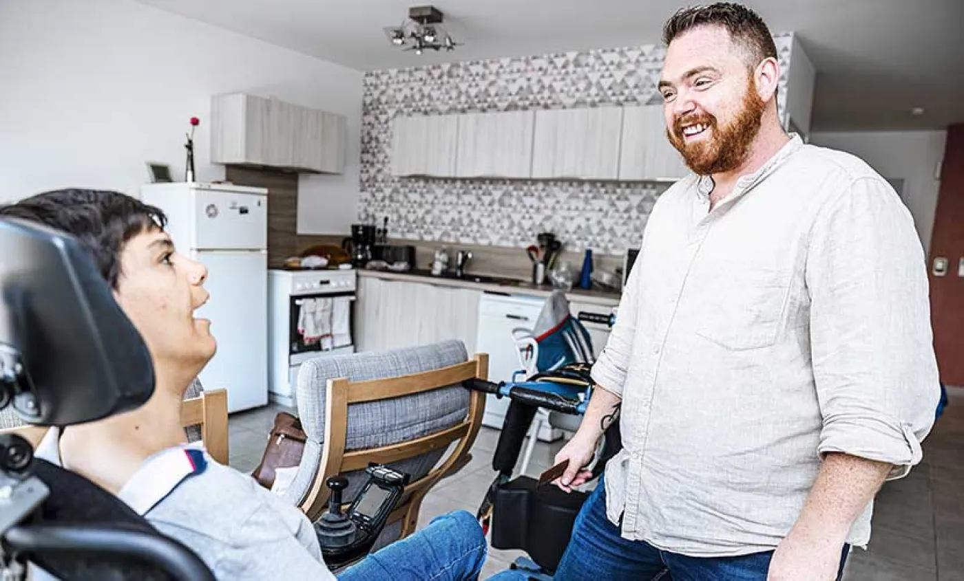 Un accompagnant éducatif et social parle avec une personne en situation de handicap